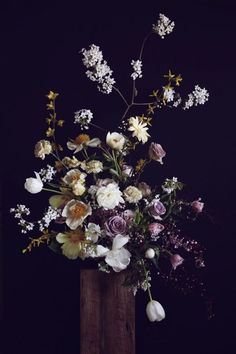 a wooden vase filled with lots of flowers