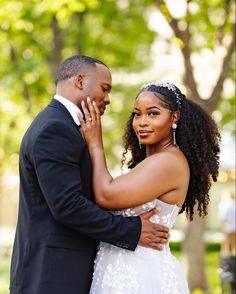 a bride and groom embracing each other in front of trees