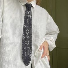 a woman wearing a white shirt and black tie holding her hand out to the side