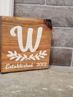 a wooden sign with the letter w on it sitting next to a brick wall in front of a door