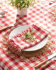 a red and white checkered table cloth on a wicker place setting with flowers