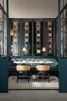 an elegant dining room with blue walls and glass partitions that lead into the sitting area