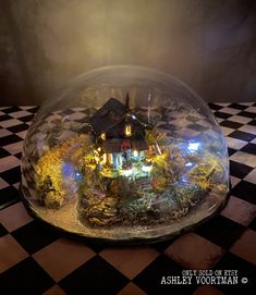 a snow globe with a house inside on a checkered floor