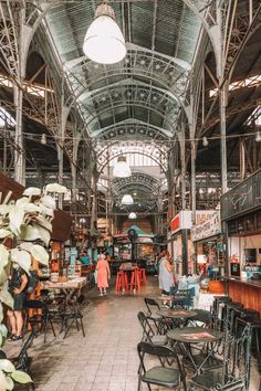 the inside of an old building with tables and chairs in front of people walking around