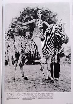 a woman is standing on top of a zebra