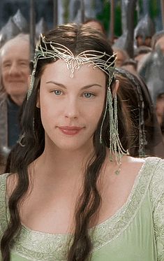 a woman with long hair wearing a tiara in front of a group of people