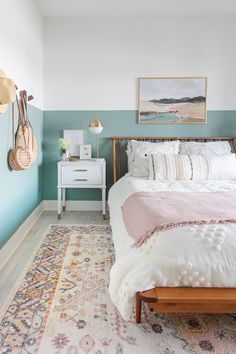 a bedroom with a bed, rug and pictures on the wall above it in shades of blue