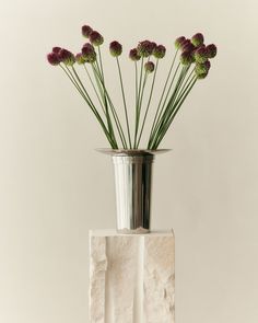 a vase with flowers in it sitting on top of a white block and some rocks