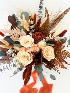 an arrangement of flowers and feathers on a white background