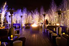 an outdoor bar with lit up trees in the background