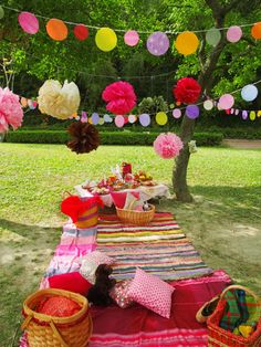 an outdoor picnic is set up in the grass and decorated with tissue pom poms