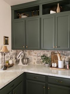 a kitchen with green cabinets and white counter tops