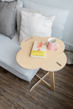 a coffee table with a book and cup on it next to a couch in a living room