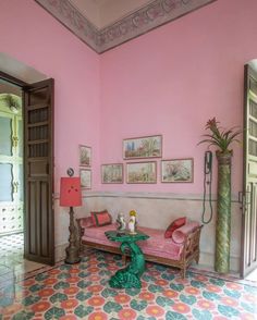 a living room with pink walls and colorful floor tiles on the floor is decorated with art