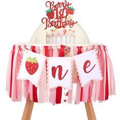 a strawberry 1st birthday banner is hanging on a table with a cake in the background