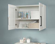 a bathroom with blue walls and white cabinetry filled with towels, toiletries and other items