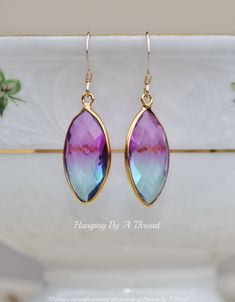 "Stunning new earrings made using bi color doublet quartz jewels. These are so pretty, and flow from a deep purple to a blue green color. Quartz is faceted and set into a gold bezel style setting. Quartz hangs from 14K gold filled french ear wires. Total earring length is 1 1/2\" long, while quartz alone are 7/8\" long. * Nickel and lead free" Multicolor Faceted Earrings For Gift, Purple Drop Earrings With Gemstone Accents, Purple Drop Earrings With Natural Stones, Purple Crystal Gemstone Drop Earrings, Purple Faceted Dangle Earrings, Purple Faceted Bead Drop Earrings, Cushion Earrings, Color Quartz, Purple Quartz