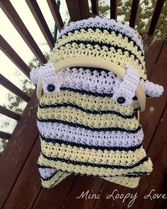 a crocheted pillow sitting on top of a wooden bench next to a fence