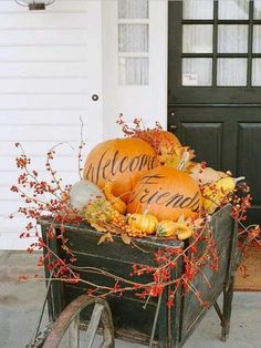 a wagon filled with pumpkins sitting in front of a door and welcome home sign