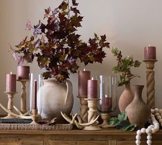 a table topped with vases filled with candles and other decorative items on top of it