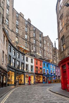 an empty street in the middle of a city filled with tall buildings and shops on either side