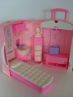 a pink dollhouse with furniture and accessories on the floor, including a small bed