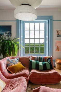 a living room filled with lots of furniture and a large window above the couches