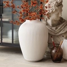 a white vase sitting on top of a table next to a statue