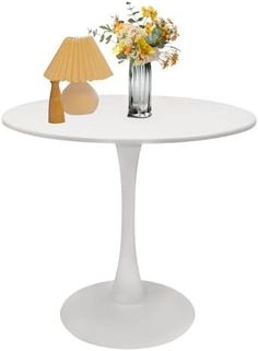 a vase with flowers on a table next to a lamp and a flower arrangement in a vase