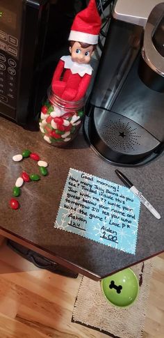 an elf is sitting on top of a counter next to a coffee maker and candy