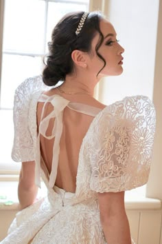 the back of a woman's wedding dress in front of a window