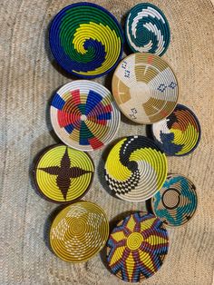 several colorful plates sitting on top of a woven table cloth next to a bowl with an ornament in the middle