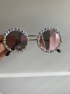 a hand holding up a pair of sunglasses with the words happy birthday on it and pearls