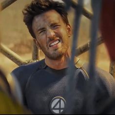 a man in a black shirt is smiling and looking out from behind a metal fence