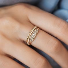 a woman's hand wearing a gold ring with three rows of diamonds on it