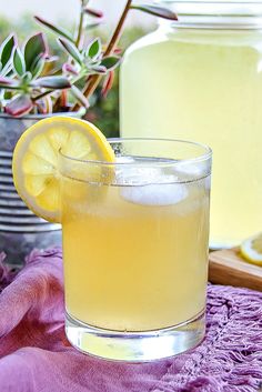 a lemonade drink in a glass next to a jar with lemons on the side