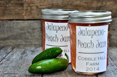 two jars filled with pickles sitting on top of a wooden table next to each other