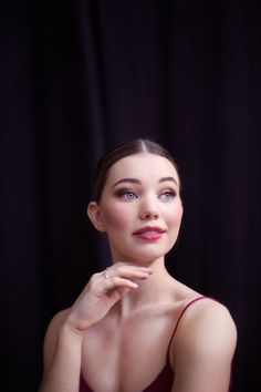 a woman in a red dress is posing for the camera with her hand on her chin