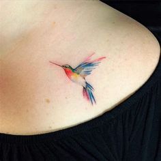 a colorful hummingbird tattoo on the back of a woman's shoulder and chest