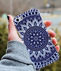 a person holding up a cell phone case with a blue and white design on it