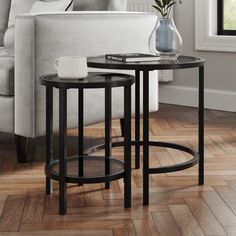 two tables with flowers on them in front of a white couch and wooden flooring