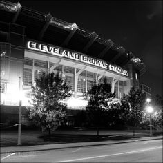 the cleveland browns stadium is lit up at night with its lights on and trees in front