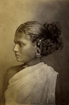 an old black and white photo of a woman in a sari with earrings on her head