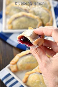 blueberry lemon hand pies on a plate with a person holding one in the foreground