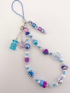 a necklace with beads and charms hanging from it's side on a white surface