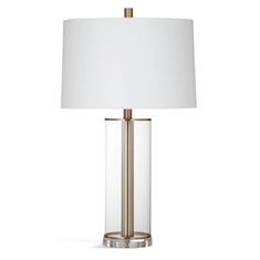 a table lamp with a white shade on the base and a gold metal frame around it