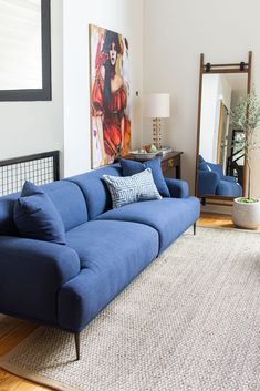 a blue couch sitting in the middle of a living room next to a large mirror