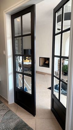 two black doors are open on the inside of a room with tile flooring and white walls