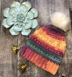 a crocheted hat with a white flower and two gold bells next to it