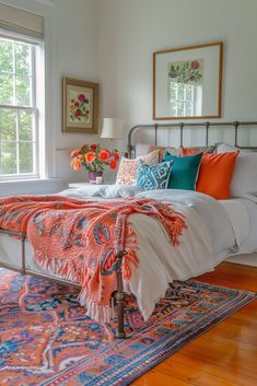 a bed with colorful pillows and blankets on top of it in a bedroom next to a window